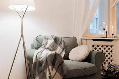 a living room with a green chair with a blanket at Musical Shelter with Balcony 2min to Republic Square in Belgrade