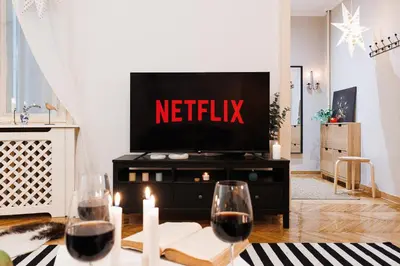 a living room with a television and two glasses of wine at Musical Shelter with Balcony 2min to Republic Square in Belgrade