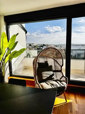 a wicker chair with pillows in a room with a window at Vracar-Luxury Penthouse in Belgrade