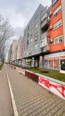 an empty street in front of a building with graffiti at Mara apartment, Belgrade, New belgrade in Belgrade