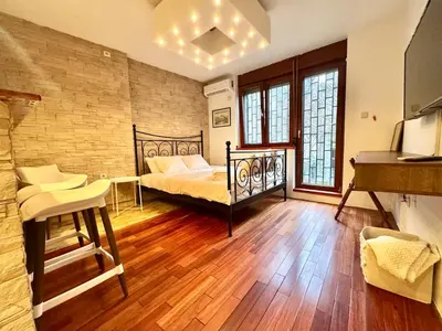 a bedroom with a bed and a table and a piano at Studio Skadarlija in Belgrade