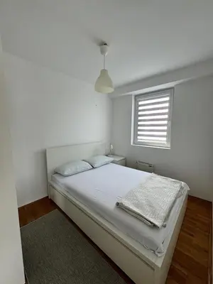 a white bedroom with a bed and a window at Lovely modern 1-bedroom with balcony in Obrenovac