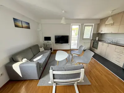 a living room with a couch and chairs and a kitchen at Lovely modern 1-bedroom with balcony in Obrenovac