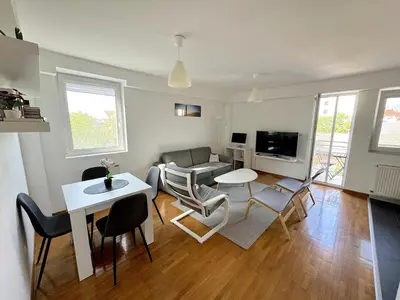 a living room with a couch and a table and chairs at Lovely modern 1-bedroom with balcony in Obrenovac