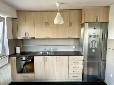 a kitchen with wooden cabinets and a stainless steel refrigerator at Lovely modern 1-bedroom with balcony in Obrenovac