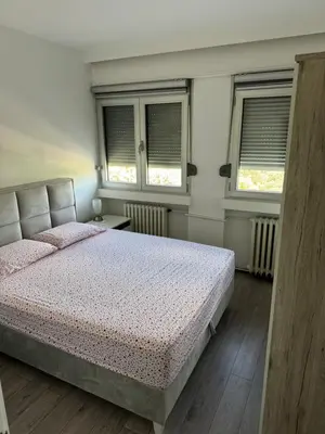 a bedroom with a bed and two windows at Marakana in Belgrade
