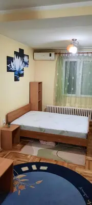 a bedroom with a bed and a table and a window at Apartman Mikica in Pančevo