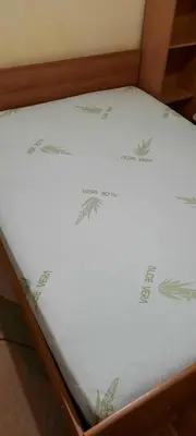 a bed with white sheets with green designs on it at Apartman Mikica in Pančevo