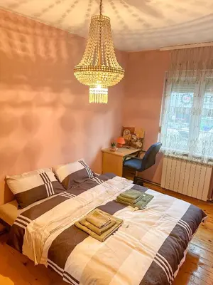 a bedroom with a large bed and a chandelier at Orhideja in Belgrade