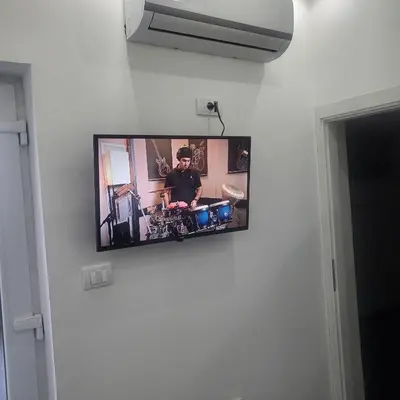 a tv on a wall with a man playing drums at Jovanovic Residence Belgrad in Belgrade