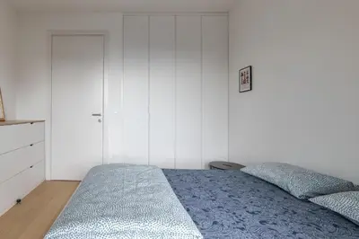 a bedroom with a bed and a white wall at HostGost Selected Suites - K District in Belgrade