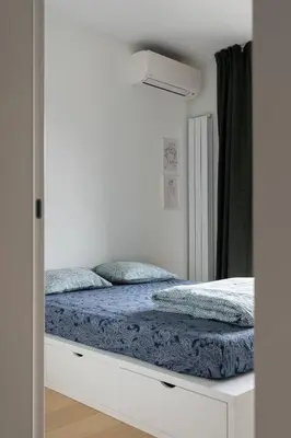 a white bedroom with a bed with blue sheets at HostGost Selected Suites - K District in Belgrade