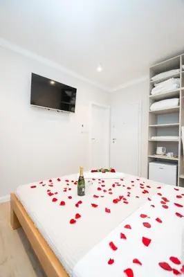 a white bedroom with a bed with red roses on it at Boho House Skadarlija in Belgrade