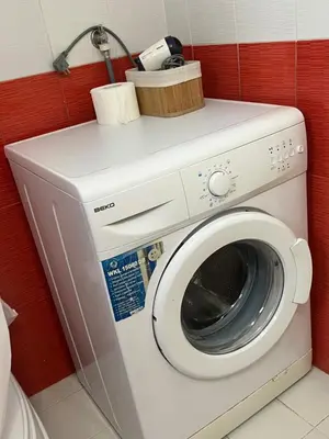 a washing machine in a bathroom with a red wall at City Vibe in Belgrade