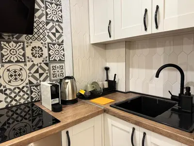 a kitchen with white cabinets and a black sink at Romero Velvet Nights in Belgrade