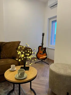 a living room with a couch and a table with a guitar at Romero Velvet Nights in Belgrade