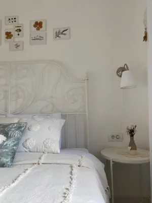 a white bed with a white headboard and a table at Vikendica Fruška lipa in Čortanovci