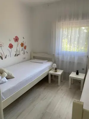 a white bedroom with a bed and a window at Vikendica Fruška lipa in Čortanovci