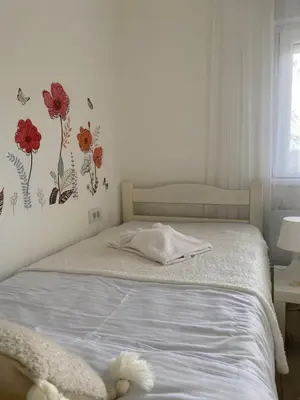 a bedroom with a bed with flowers on the wall at Vikendica Fruška lipa in Čortanovci