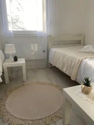 a white bedroom with a bed and a table at Vikendica Fruška lipa in Čortanovci