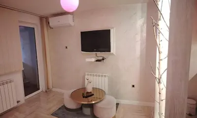 a living room with a table and a tv on the wall at Pinky Belgrade Apartment in Belgrade