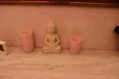 a buddha statue sitting next to three pink candles at Pinky Belgrade Apartment in Belgrade