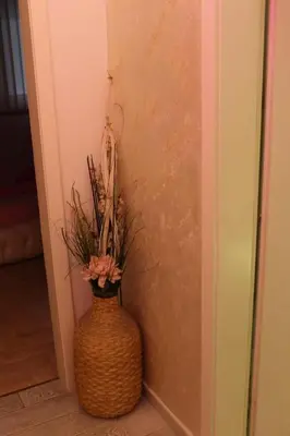 a vase with flowers in it next to a wall at Pinky Belgrade Apartment in Belgrade