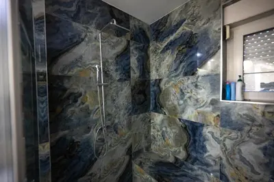 a shower in a bathroom with a stone wall at Aries apartment in Belgrade in Belgrade