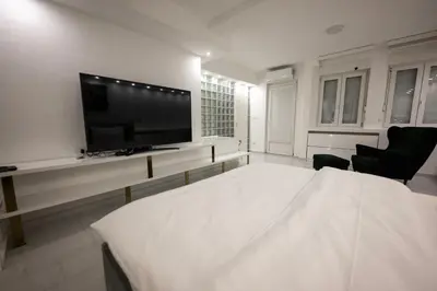 a white living room with a tv and a table at Aries apartment in Belgrade in Belgrade