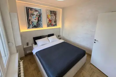 a bedroom with a bed with two paintings on the wall at Arena Lux apartment in Belgrade