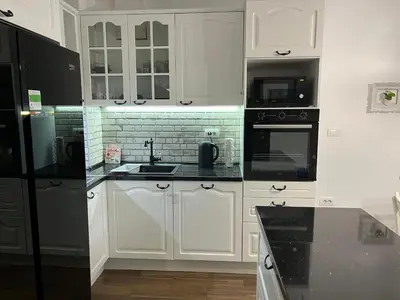 a kitchen with white cabinets and black appliances at Costa apt 3 bedrooms Ideal for Groups Near Arena in Belgrade
