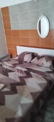 a bed with a camouflage blanket and a mirror at Small apartment with private bathrooms STRONG INTERNET in Belgrade