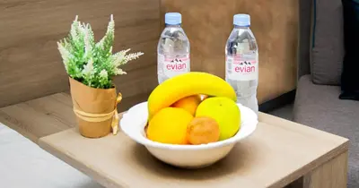a bowl of fruit on a table with two bottles of water at Garni Hotel Mint in Belgrade