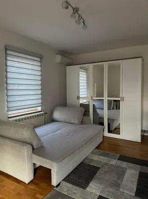 a bedroom with a bed and a couch and windows at Apartman Tara2 in Belgrade
