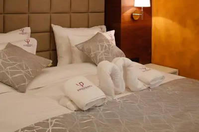 a hotel room with a pile of towels on a bed at Passpartu Garni hotel Rooms in Belgrade