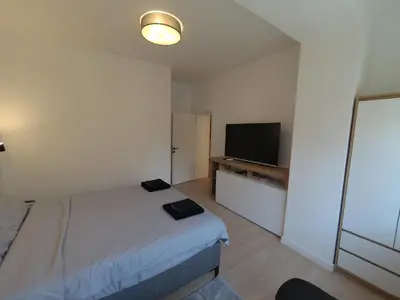 a bedroom with a bed and a flat screen tv at Aster Apartmani in Belgrade