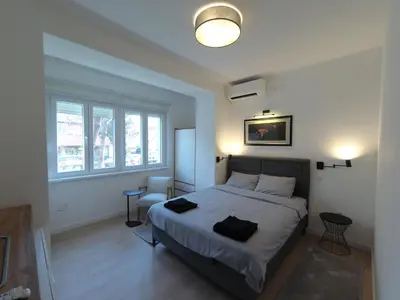 a bedroom with a bed and a large window at Aster Apartmani in Belgrade