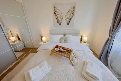 a large white bed with a tray of food on it at Eternal Lux Belgrade Waterfront in Belgrade