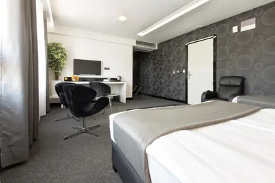 a hotel room with a bed and a desk and chairs at Nova City Garni Hotel Signature Collection in Belgrade