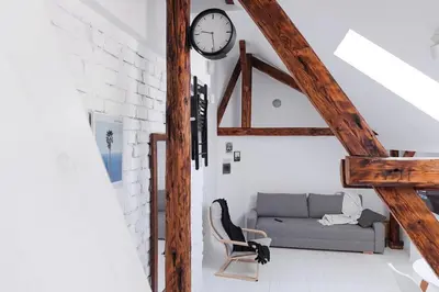 a living room with a couch and a clock on the wall at Charming attic in the heart of the city in Belgrade