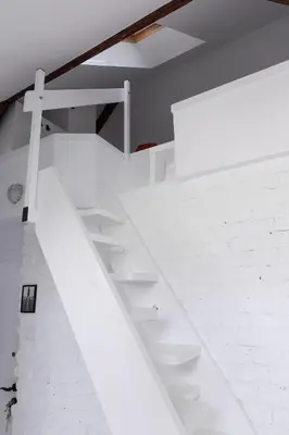 a white staircase in a room with a white brick wall at Charming attic in the heart of the city in Belgrade