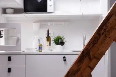 a white kitchen with a bottle of wine on a counter at Charming attic in the heart of the city in Belgrade