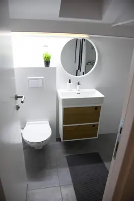 a white bathroom with a toilet and a mirror at Charming attic in the heart of the city in Belgrade