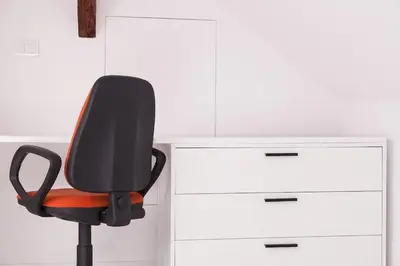 a black and orange office chair next to a white cabinet at Charming attic in the heart of the city in Belgrade