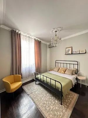 a bedroom with a bed and a chair and a chandelier at Yulia's beautiful studio in Belgrade