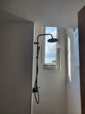 a shower in a bathroom next to a window at Yulia's beautiful studio in Belgrade