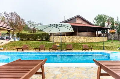 a swimming pool with chairs and an umbrella at Alrawda Resort in Mala Ivanča