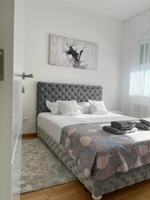 a bedroom with a large bed with a gray headboard at Apartman Relax in Arandjelovac