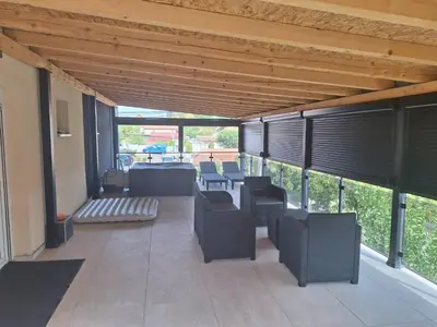a covered patio with chairs and tables and windows at Apartmani Lux Filipovic in Smederevo