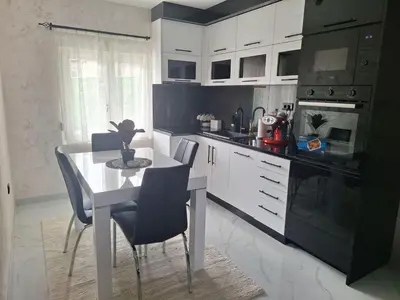a kitchen with white cabinets and a white table and chairs at Apartmani Lux Filipovic in Smederevo